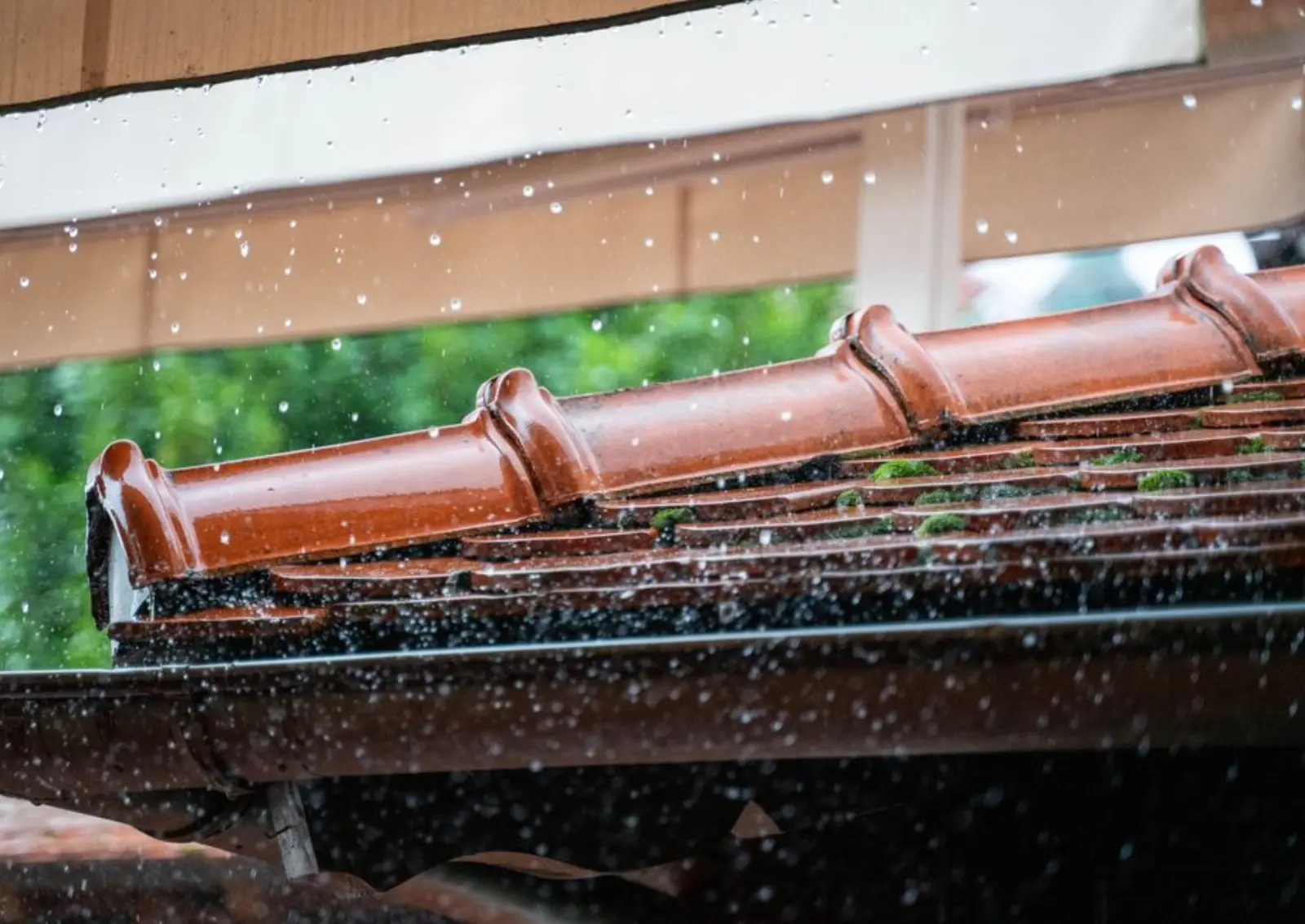 Detailed view of rain droplets cascading off a terracotta roof, capturing the essence of a rainy day.